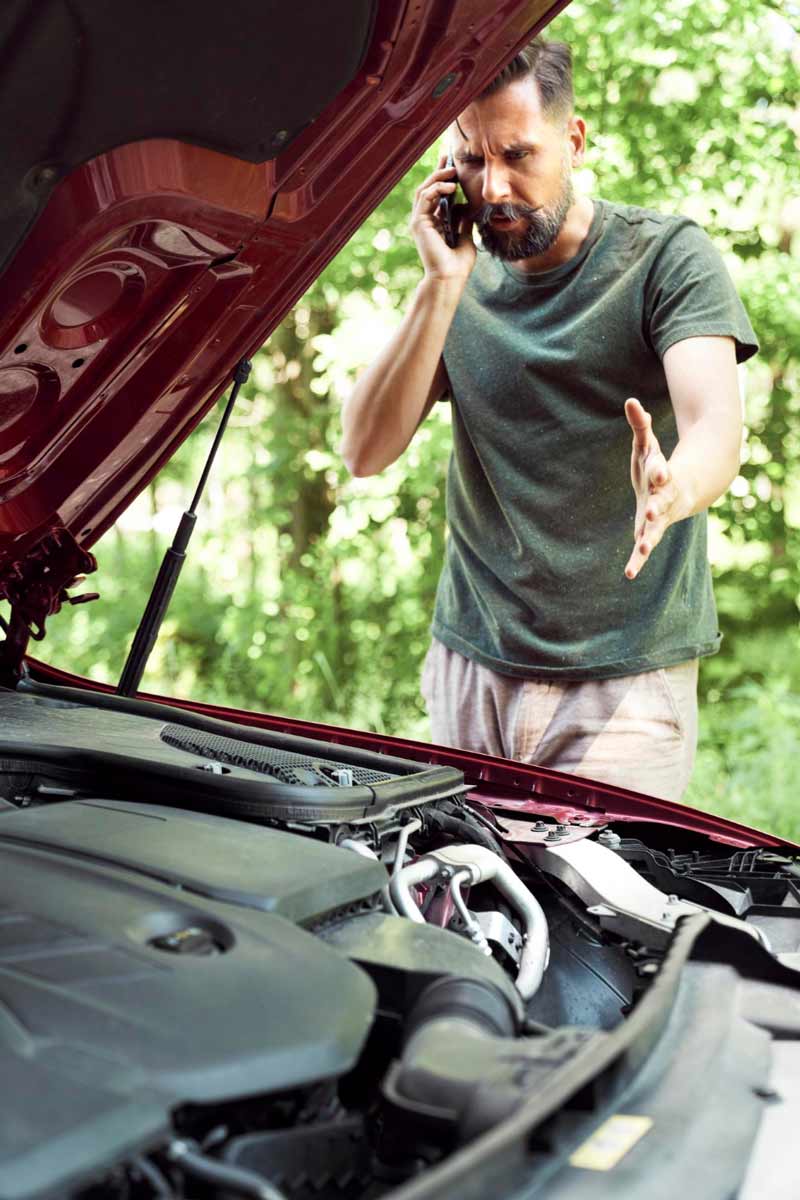 Junger Mann prüft Getriebeschaden bei Schrottauto Ankauf Kreuztal